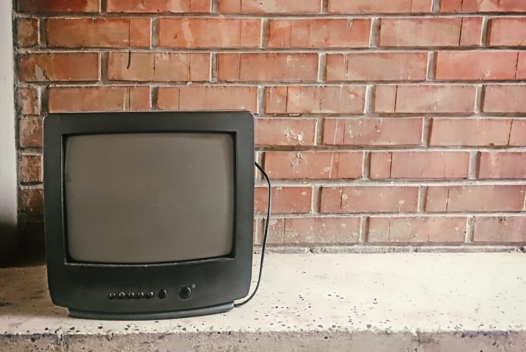 Abandoned old tv against brick wall